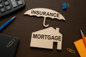 Wooden mortgage house icon and insurance umbrella on a dark desk with office stationery, symbolising home loan protection and insurance concepts.