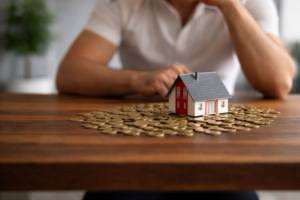 Model house placed on stacked coins representing home loan refinancing and mortgage repayment comparison using a refinance house loan calculator