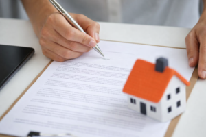 Person signing a fixed price building contract with a house model, showing fixed price contract home building agreement in Australia