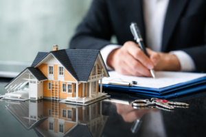 Speak with a home loan broker to compare lenders and secure the right mortgage Home loan broker reviewing mortgage documents next to a model house, representing expert guidance for securing the right home loan in Australia